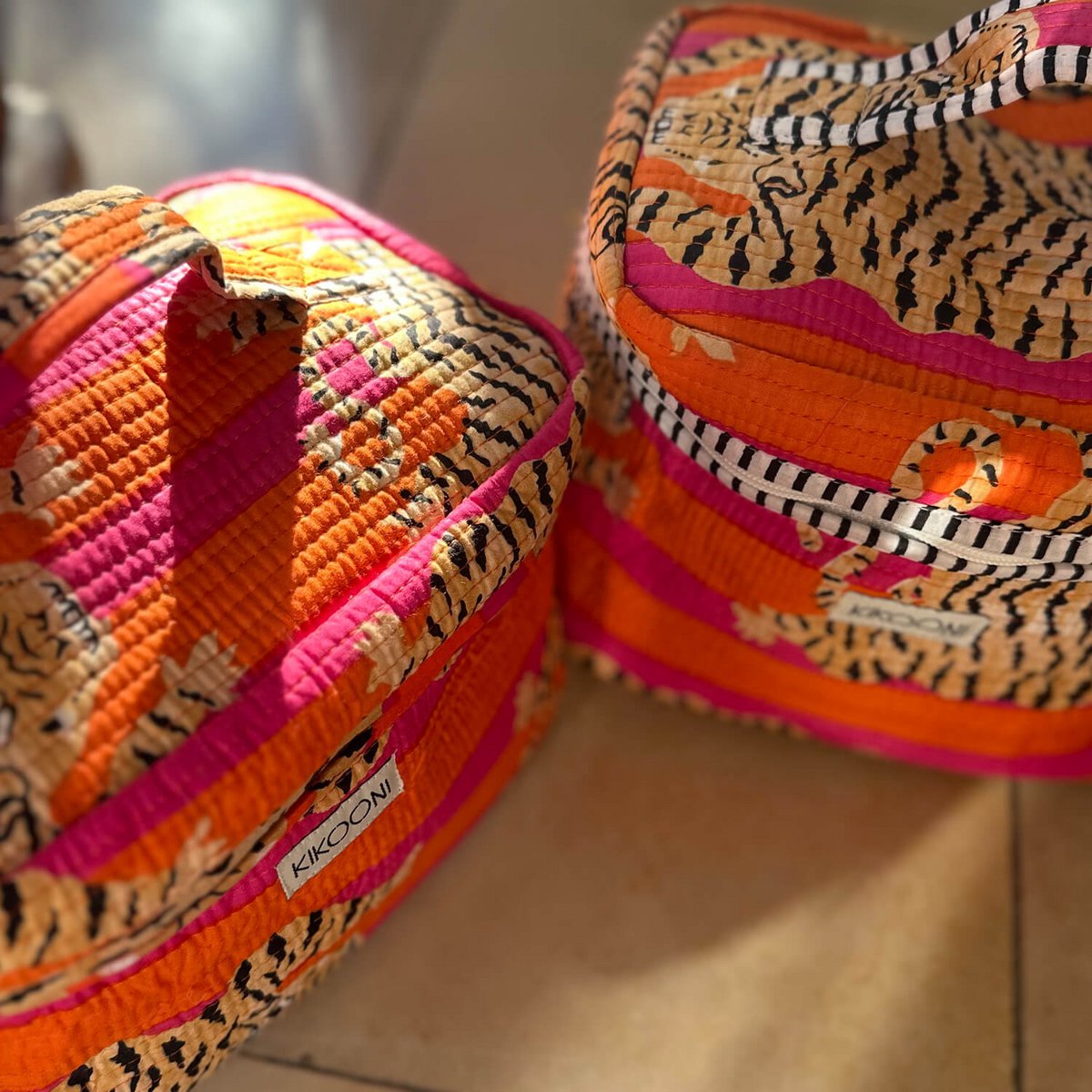 Vrolijke handelsmerk Kikooni gestreepte oranje roze kussens met etnische prints op vloer