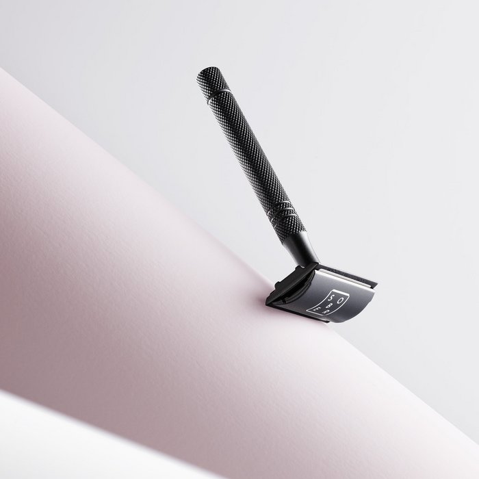 Strakke zwarte scheermes met tekst op glad oppervlak, minimalistische verzorgingsfoto