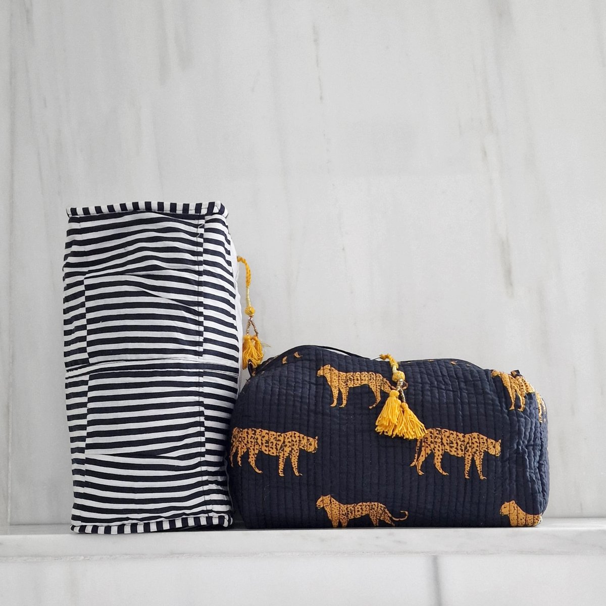 Gerolde zwart-wit gestreepte mat en blauwe tas met geel panterprint en kwastjes op marmeren achtergrond