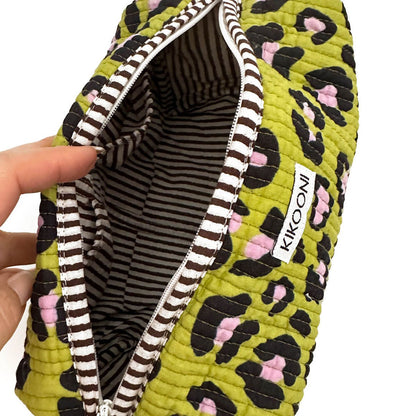 Hand houdt groene etui met zwarte en roze leopardprint en gestreepte binnenkant