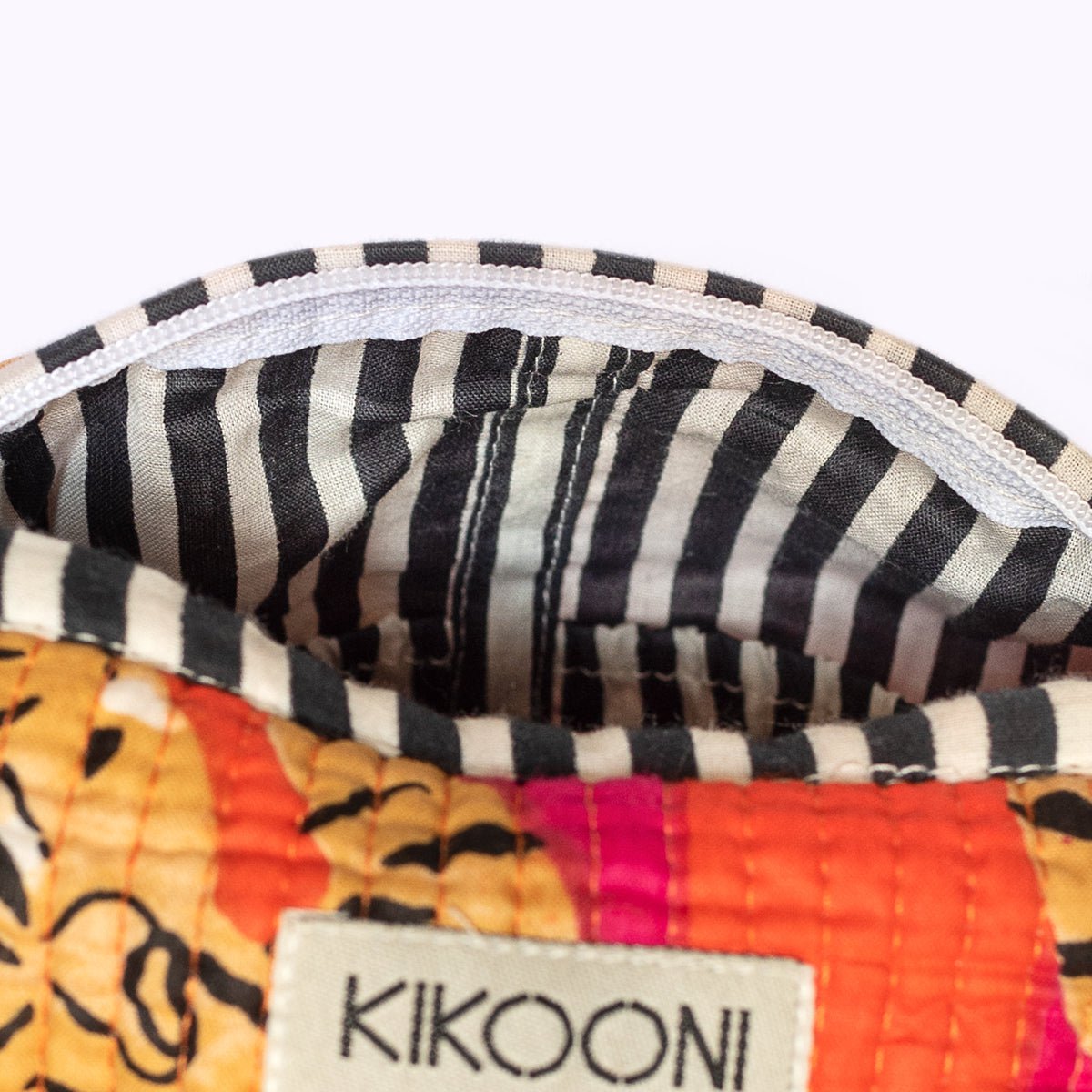 Close-up van kleurrijke stoffen tas met zwart-witte gestreepte voering en merklabel KIKOONI