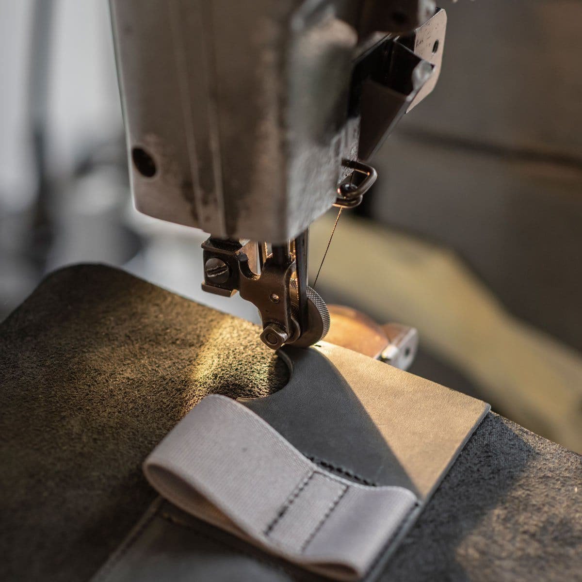 Close-up van naaien met naaimachine op grijs leer en stof in werkplaats