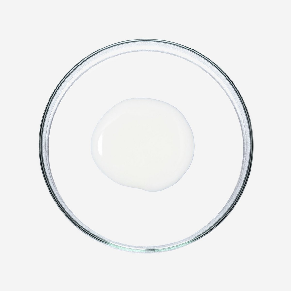 Doorzichtige glazen schaal met een witte vloeistof op witte achtergrond