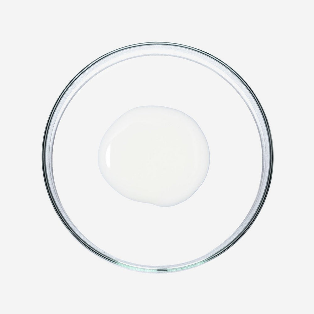 Doorzichtige glazen schaal met een witte vloeistof op witte achtergrond