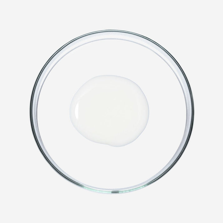 Doorzichtige glazen schaal met een witte vloeistof op witte achtergrond