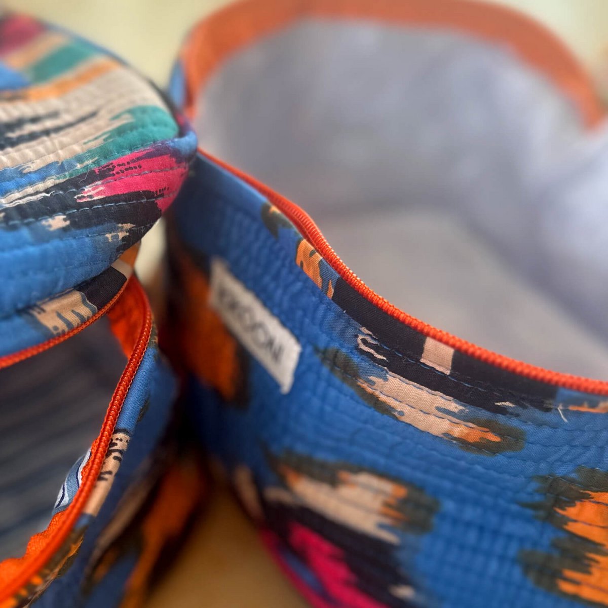 Close-up van blauwe, oranje en roze stoffen manden met abstract patroon en rode bies