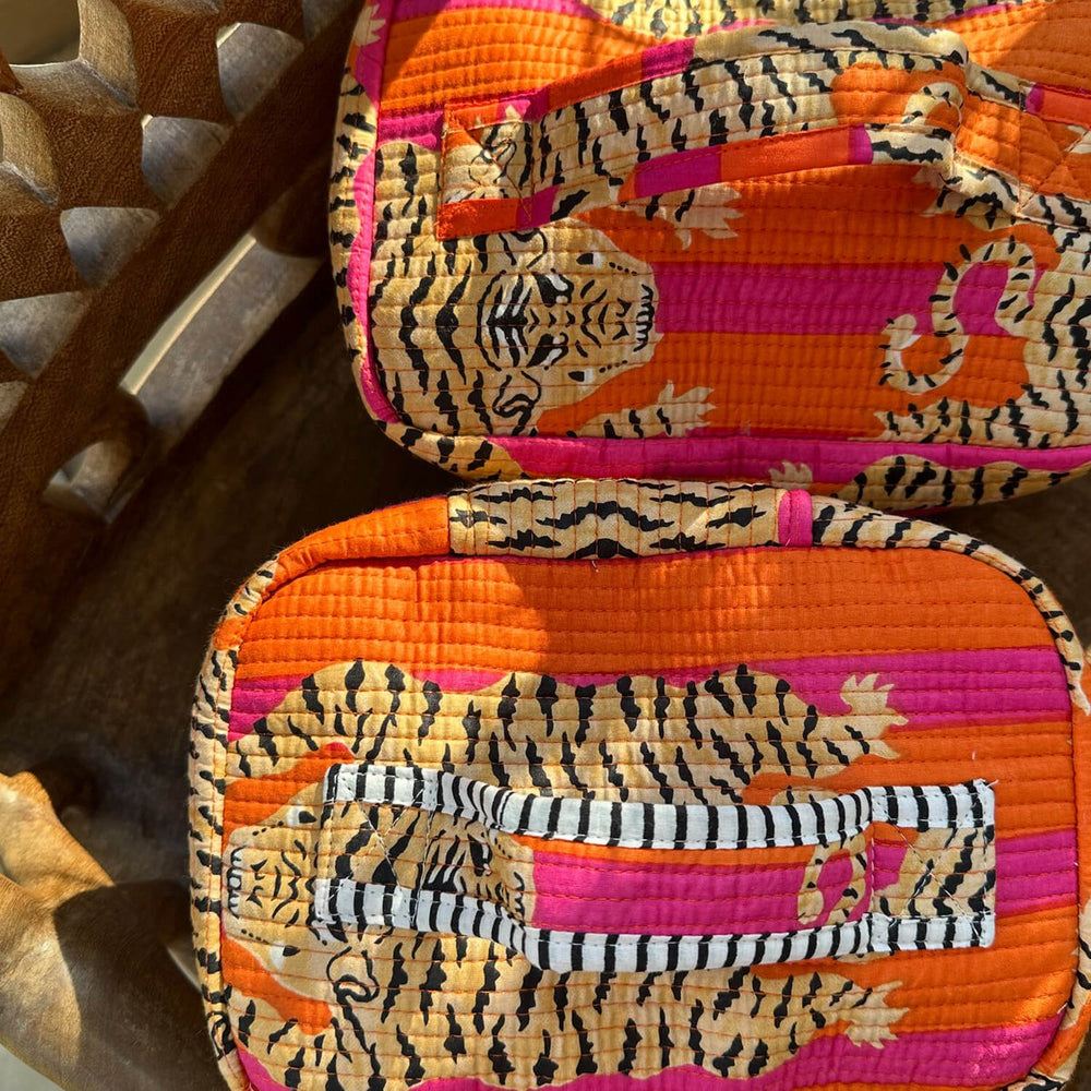 Oranje en roze quilted tassen met tijgerprint en gestreepte handvatten op houten oppervlak